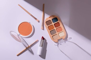 Hafif arkaplanda kozmetik ürünler ve makyaj fırçaları