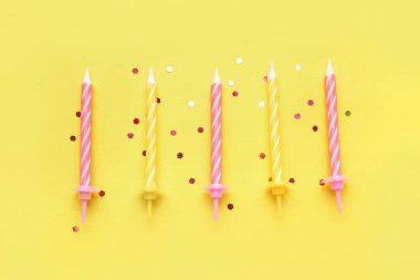 Sarı arka planda doğum günü mumları ve simler
