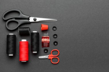 İplik makaralı kompozisyon ve koyu arkaplanda dikiş malzemeleri