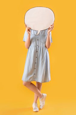 Sarı arka planda boş konuşma balonunun arkasına saklanan genç bir kadın.