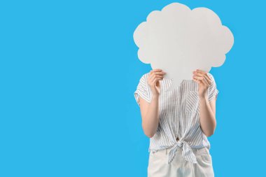 Mavi arka planda boş konuşma balonunun arkasına saklanan genç bir kadın.