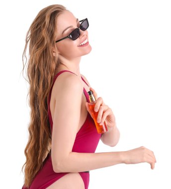 Beyaz arka plana güneş kremi süren güzel genç bir kadın.