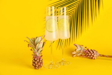 Limonlu kokteyl bardakları ve sarı arka planda bebek ananasları.