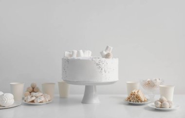 Doğum günü pastası ve şekerler duvarın yanındaki beyaz masada.