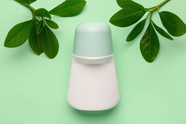 Açık yeşil arka planda bitki dalları olan deodorant