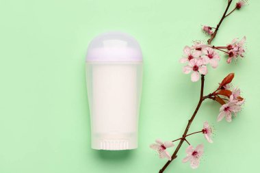 Açık yeşil arka planda çiçek açan dallı deodorant