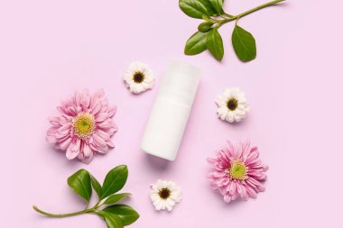 Çiçekli deodorant ve pembe arka planda yapraklar
