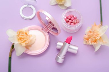 Leylak arka planında farklı kozmetik ürünleri olan güzel nergisler.