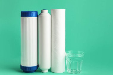 Yeşil arkaplanda bir bardak sıvı ve su filtresi.