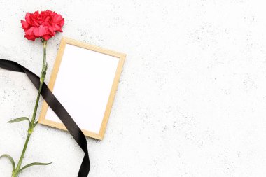 Siyah kurdeleli kırmızı karanfil ve beyaz grunge arkaplanda fotoğraf çerçevesi