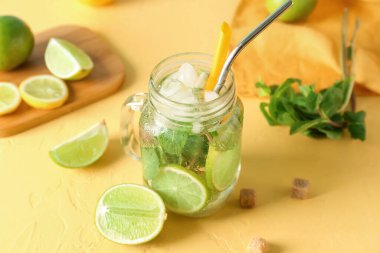 Sarı arka planda bir kavanoz lezzetli mojito.