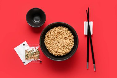 Çubuklu ve kırmızı arka planda baharatlı hazır erişteler.