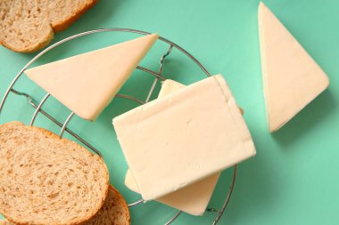 Turkuaz arka planda işlenmiş peynir ve ekmeğin yanında dur