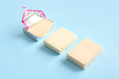 Mavi arkaplanda folyo içinde işlenmiş peynir