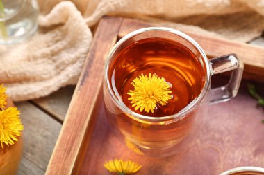 Tahta arka planda cam bardak sağlıklı karahindiba çayı.