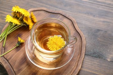 Tahta arka planda cam bardak sağlıklı karahindiba çayı.