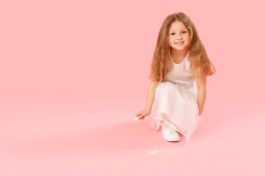 Pembe arka planda tebeşirle çizen küçük kız. Çocuk Bayramı kutlaması