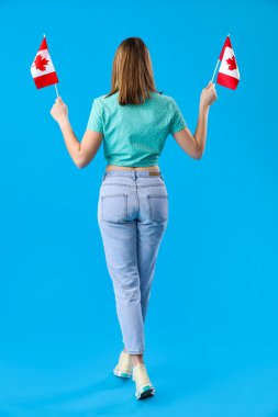 Mavi arka planda Kanada bayrakları olan genç bir kadın.