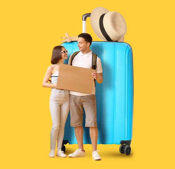 一对年轻的游客带着黄色背景的硬纸板和大手提箱 — 图库照片