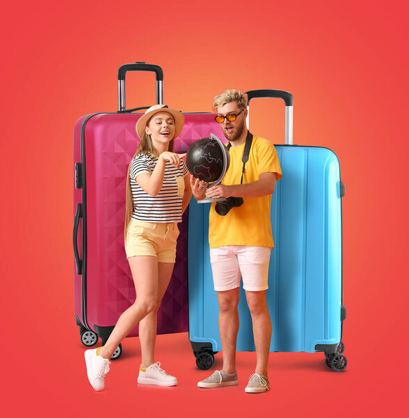 Couple of tourists with globe and big suitcases on red background