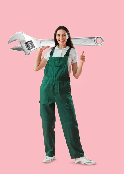 Vrouwelijke Werknemer Met Grote Verstelbare Moersleutel Met Duim Roze Achtergrond — Stockfoto
