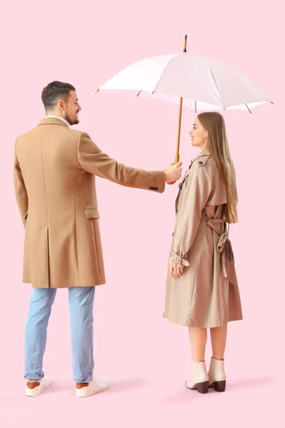 Mladý Muž Drží Deštník Pro Svou Ženu Růžovém Pozadí — Stock fotografie