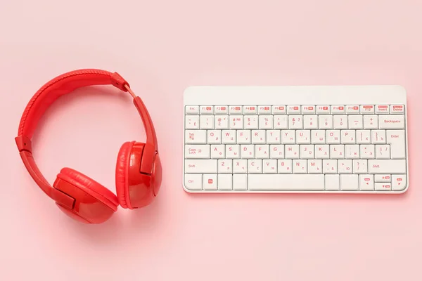 Composition with keyboard and headphones on pink background