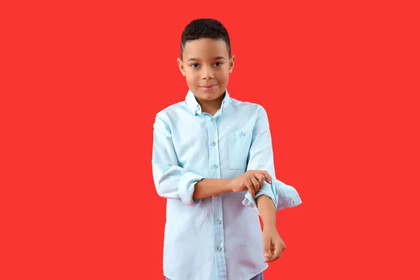 Μικρό Αφροαμερικανό Αγόρι Που Σηκώνει Μανίκι Του Στο Κόκκινο Φόντο — Φωτογραφία Αρχείου