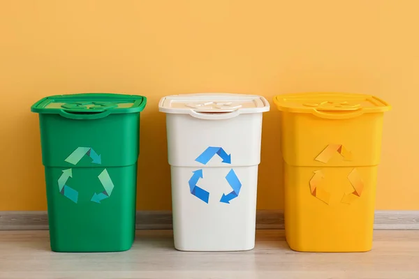黄色の壁の近くにリサイクルのシンボルを持つ異なるゴミ箱 — ストック写真