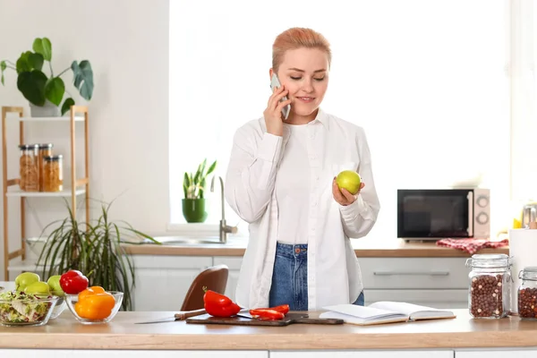 Ung Kvinna Med Äpple Pratar Mobiltelefon Köket — Stockfoto