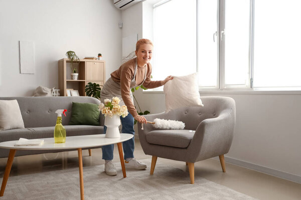 Молодая женщина убирает кресло с pp-пылесосом дома