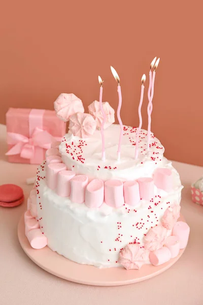 濃いベージュの壁の近くの白いテーブルの上にキャンドルやお菓子と誕生日ケーキ — ストック写真