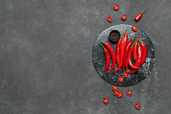 Slate board with fresh chili peppers on dark background