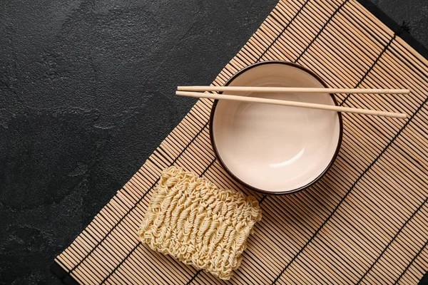 Raw Instant Noodles Bowl Chopsticks Bamboo Mat Black Grunge Background — Stock Photo, Image