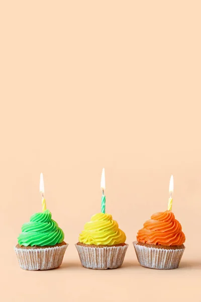 ベージュの背景に誕生日キャンドルとおいしいカップケーキ — ストック写真