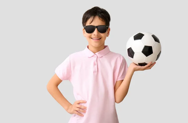 Malý Chlapec Fotbalovým Míčem Nosí Sluneční Brýle Šedém Pozadí — Stock fotografie