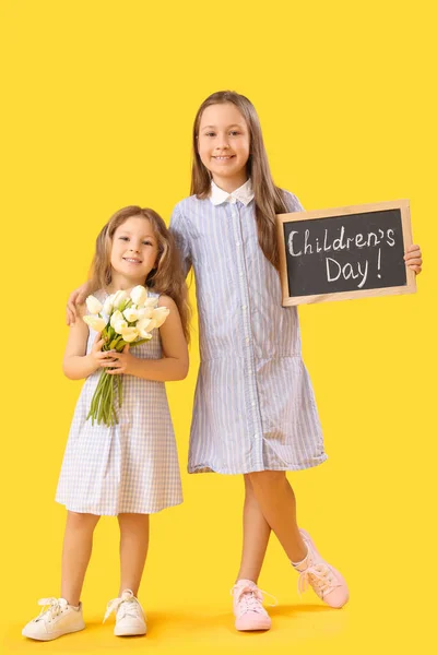 小さな女の子開催Chalkboardともにテキスト子供の日とチューリップ上の黄色の背景 — ストック写真