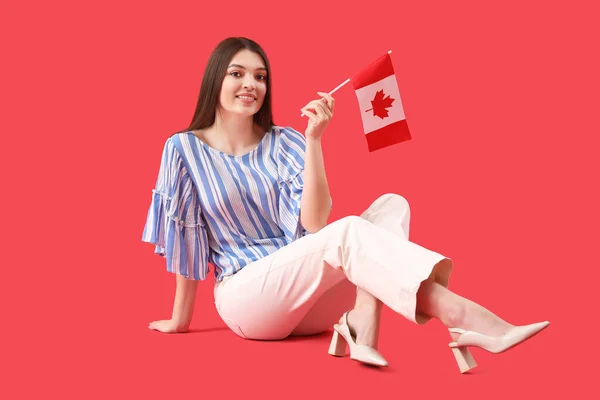Młoda Kobieta Flagą Kanady Siedzi Czerwonym Tle — Zdjęcie stockowe