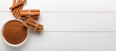 Tarçın tozu ve beyaz ahşap masaya sopa ile kase. Tasarım için pankart