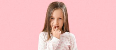 Little girl biting nails on pink background