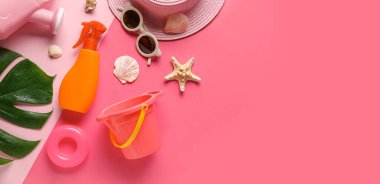 Pembe arka plandaki çocuklar için güneş kremi ve plaj aksesuarları.