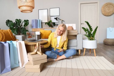 Evde cep telefonu ve yeni ayakkabıları olan olgun bir kadın. İnternetten alışveriş