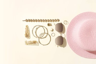 Güneş gözlüklü şık mücevherler ve açık arkaplanda yaz şapkası.