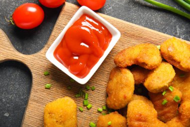 Lezzetli külçeler, ketçap ve domatesler siyah masada.