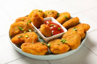 Lezzetli nugget tabağı, bir kase ketçap ve beyaz fayanslı yeşil soğan.