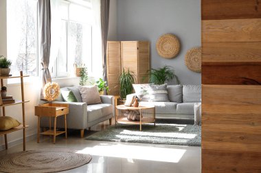 Koltukları, çiçekleri ve masası olan aydınlık oturma odasının içinde.