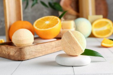 Banyo bombaları, portakallar ve siyah grunge duvarının yanındaki masada yapraklar.