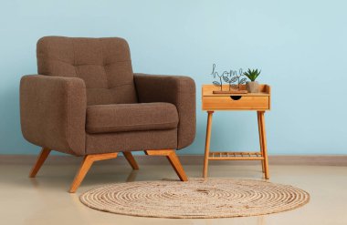 Açık mavi duvarın yanındaki koltuklu ve masalı odanın içi.