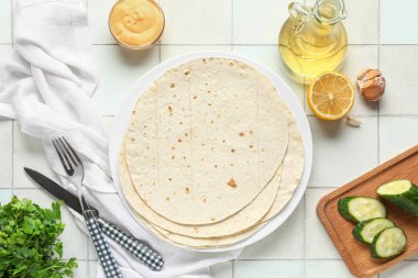 Taze lavaş, salatalık, yağ ve soslu beyaz fayanslı tabak.