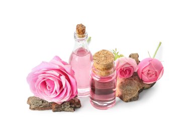 Beyaz arka planda gül özü ve çiçekli kozmetik yağı şişeleri